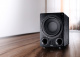 Magnat Alpha RS12 subwoofer, svart En svart subwoofer med rund högtalare och två portar.