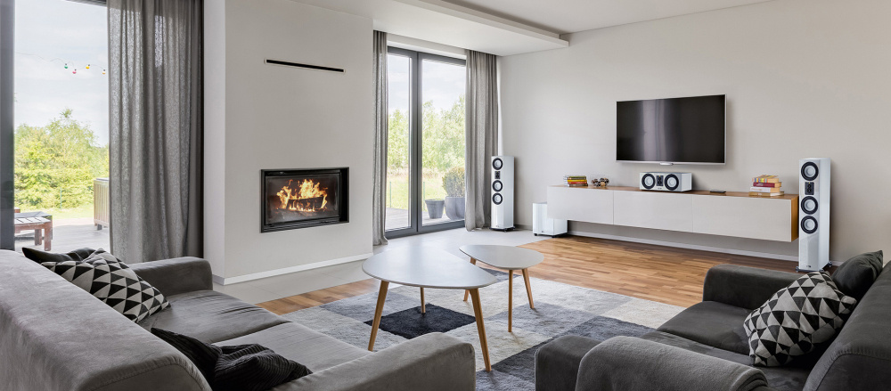 Modernt vardagsrum med vit golvhögtalare och öppen spis.
