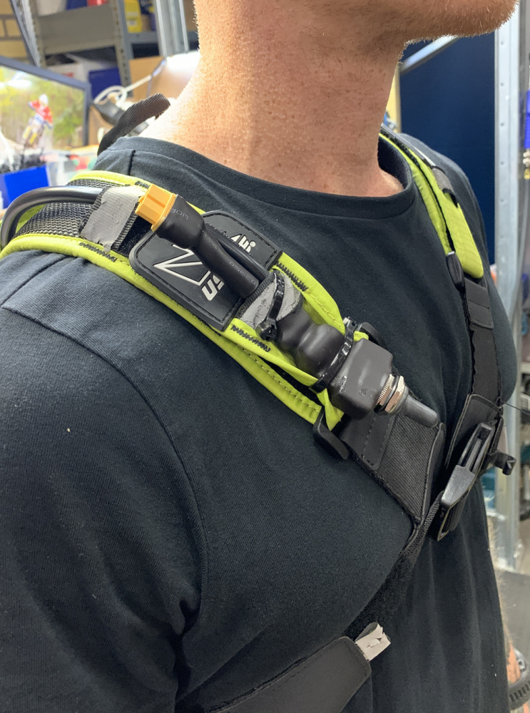 En person bär en axelrem med ljus och utrustning för Nizled hjälmkit.