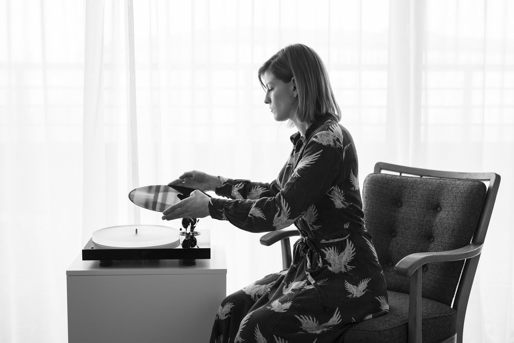 En kvinna placerar en vinylskiva på en skivspelare.