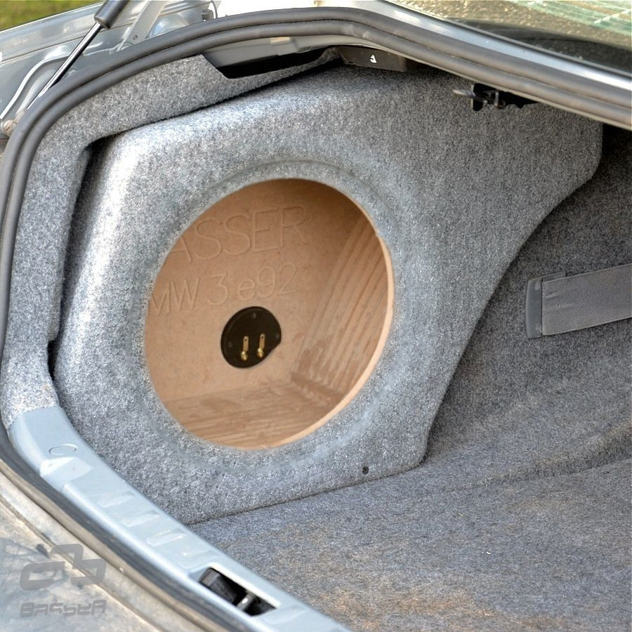 Ett bakluckeutrymme med en rund högtalarlåda av trä insvept i grått tyg.