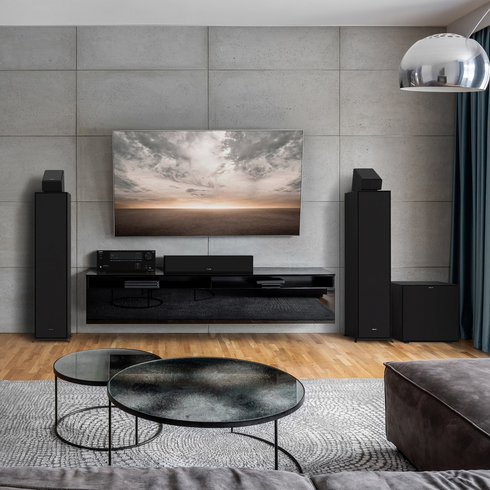 Ett modernt vardagsrum med svarta högtalare, TV och stilrena möbler.