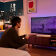 Sonos Ray & Sub Mini 2.1 soundbarpaket, vit En person spelar videospel framför en TV med en Sonos Ray soundbar.
