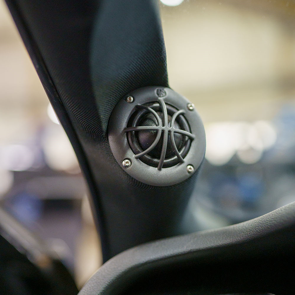 En liten högtalare med galler, installerad i bilens interiör.