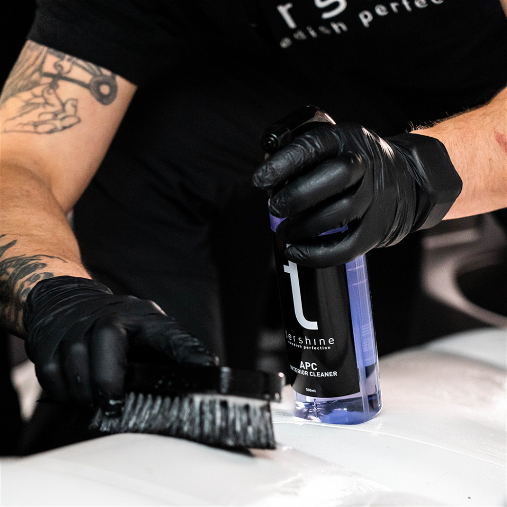 En person använder Tershine interiörtvättspaket med sprayflaska och borste.