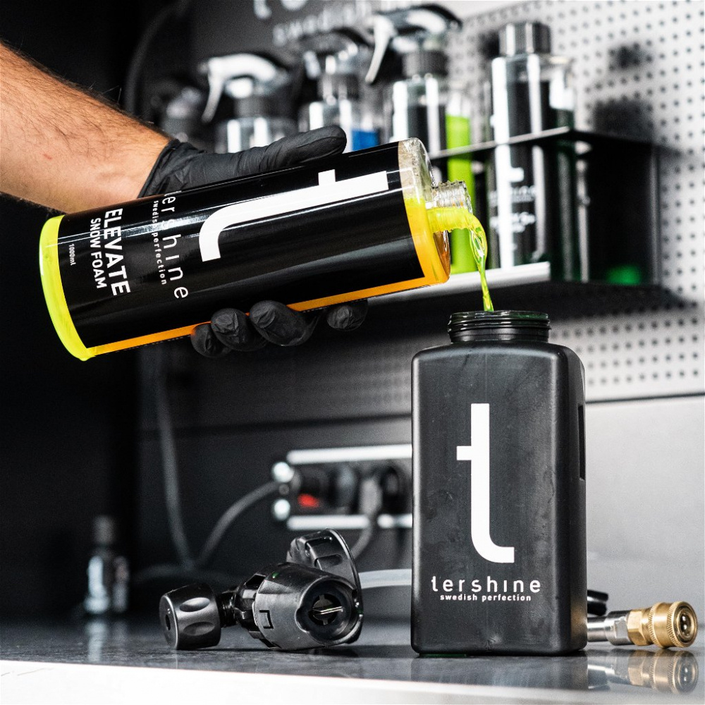 En person häller en grön vätska i en svart behållare.