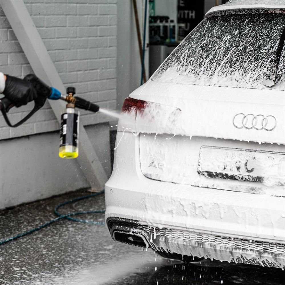 En person sprayar ett schampo på en vit Audi-bil.